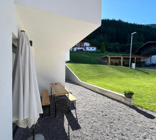 a table and a chair next to a building with a umbrella at Apartment Oberleins II in Arzl im Pitztal