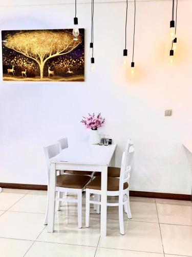 a white table and chairs in a room with a painting at Rio House district 10 Saigon Centrosa in Ho Chi Minh City