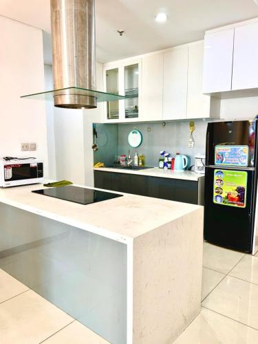 a kitchen with white cabinets and a black refrigerator at Rio House district 10 Saigon Centrosa in Ho Chi Minh City