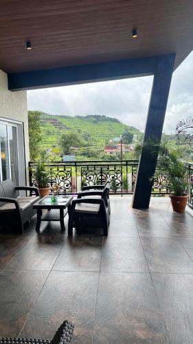a room with a balcony with a table and chairs at 4BHK Cozy Villa with Pvt Pool in Panchgani