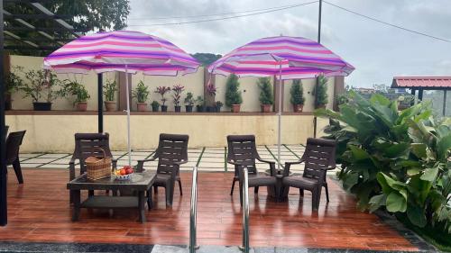 a table and chairs and umbrellas on a patio at 4BHK Cozy Villa with Pvt Pool in Panchgani