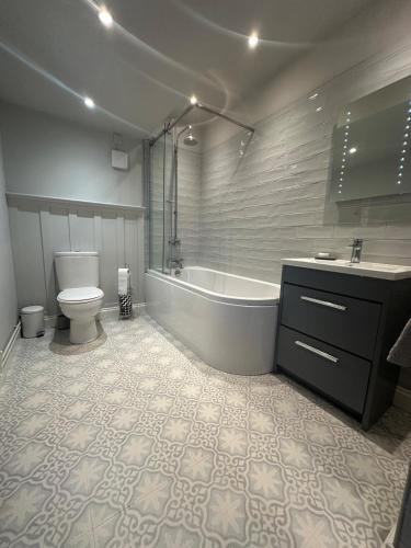 a bathroom with a tub and a toilet and a sink at Garden cottage at The Glebe in Bayton