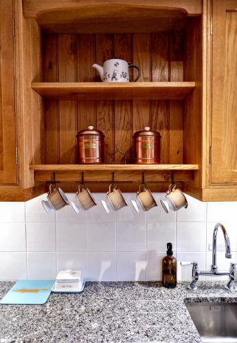 a kitchen counter with pots and pans on a shelf at Mountain View Farm Cottage in Crickhowell
