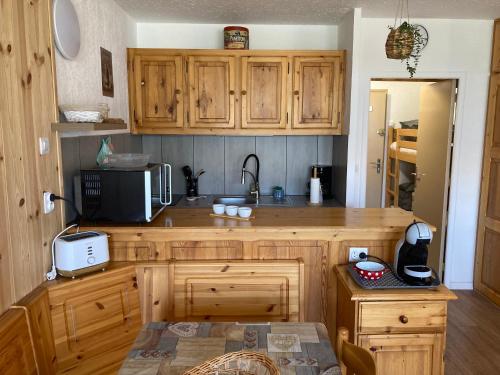 a kitchen with wooden cabinets and a microwave at Studio standing PRALOUP 1600 dernier étage 4 personnes Vue époustouflante in Uvernet-Fours