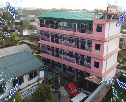 a pink building with a car parked in front of it at Hotel Alohi Ghar in Jorhat