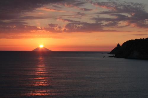a sunset over the ocean with a mountain in the background at Le Casette Sul Mare in Capo Vaticano