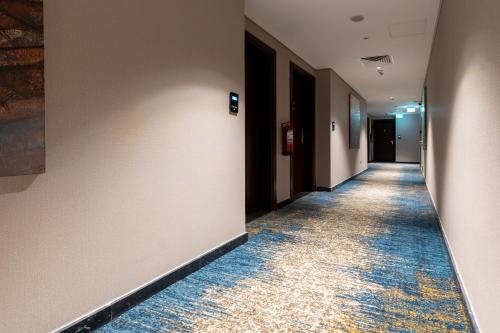 an empty hallway with a long hallway with a blue carpet at Lumian Hotel in Al Madinah