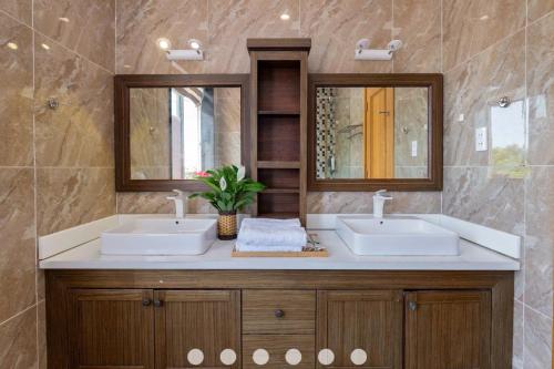 une salle de bain avec deux lavabos et deux miroirs dans l'établissement Villa Hồ Bơi Trần Văn Thời khu Du Lịch Tháp Tam Thắng, à Vung Tau