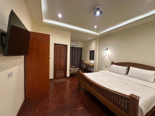 a bedroom with a bed and a flat screen tv at Prince Hotel Chiang Mai in Chiang Mai