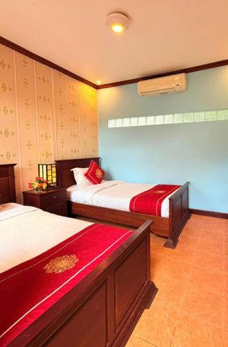 a bedroom with two beds with red sheets at Luang Prabang Manichan Villa in Luang Prabang