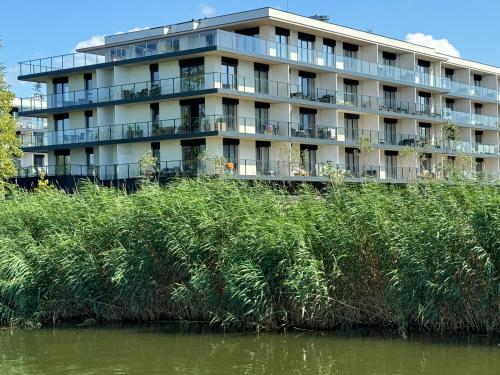 a large building with balconies on the side of a river at Apartament z widokiem Dziwnów & Spa, in Dziwnów