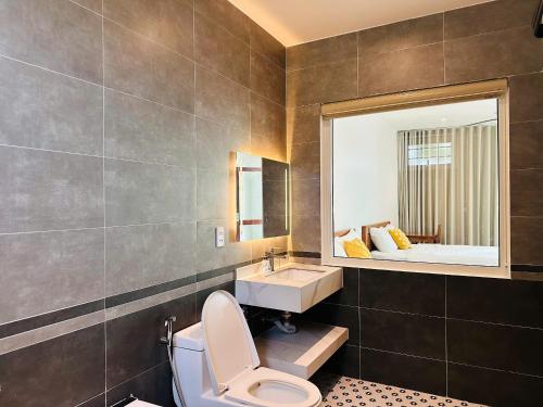 a bathroom with a toilet and a sink and a mirror at Myhoa Lagoon - Kiting Town in Phan Rang