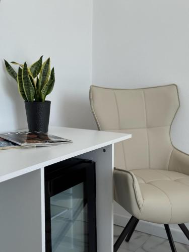 a white desk with a chair and a potted plant at Hotel Avra in Aegina Town
