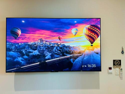 a flat screen tv hanging on a wall with hot air balloons at Myhoa Lagoon - Kiting Town in Phan Rang