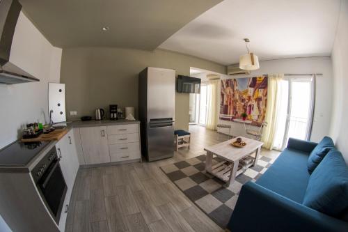 a living room with a blue couch and a kitchen at Sappho Plomari in Plomarion