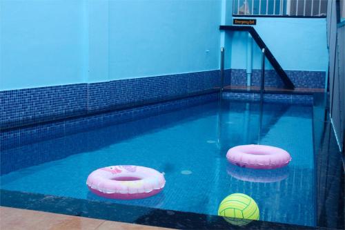 a swimming pool with two pink inflatables in the water at VGK Residency in Wayanad