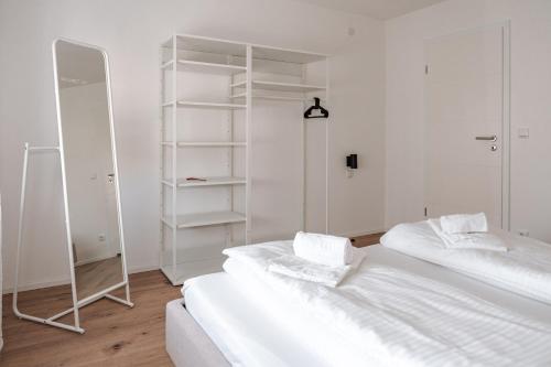 a white room with two beds and a mirror at Skyrise Apartments - Stilvoll wohnen, entspannt genießen in Bad Wörishofen
