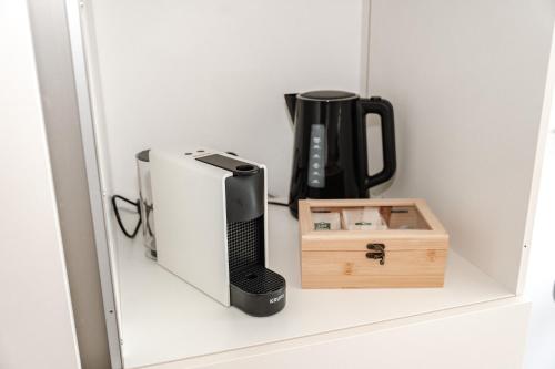 a black appliance and a box on a shelf at Skyrise Apartments - Stilvoll wohnen, entspannt genießen in Bad Wörishofen