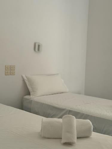 two beds in a white room with towels on them at Hotel Avra in Aegina Town