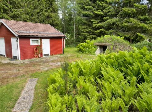 a small red house in a yard with trees at Paradise in Bergslagen in Fagersta