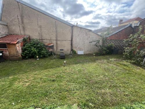 Un patio trasero con un muro y un patio con una boca de incendios en Studios privatifs avec vue sur Jardin, en Sannois