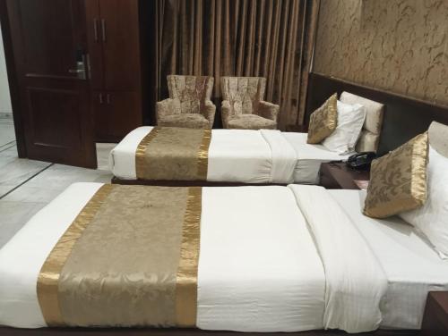 two beds in a hotel room with two chairs at Monarch Residency Gurgaon in Gurgaon