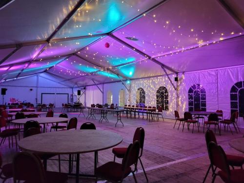 a marquee with tables and chairs and purple lights at Château de la Garlais - 29 couchages in Derval