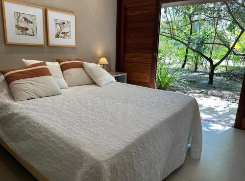 a bedroom with a large white bed and a window at Canto das Pedras House in Mata de Sao Joao