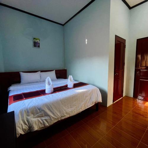 a bedroom with a large bed with two hats on it at สไมล์เกสต์เฮาส์ วังเวียง in Vang Vieng