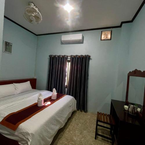 a bedroom with a bed and a window with curtains at สไมล์เกสต์เฮาส์ วังเวียง in Vang Vieng