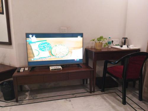 a flat screen tv sitting on a wooden table with a chair at Monarch Residency Gurgaon in Gurgaon