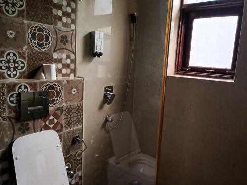 a small bathroom with a toilet and a window at Monarch Residency Gurgaon in Gurgaon