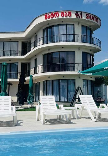 a building with chairs and a pool in front of it at Shato Mash in Tbilisi City