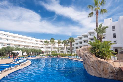 a swimming pool with chairs and a resort at Aparthotel Tropic Garden in Santa Eularia des Riu