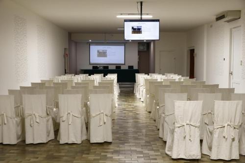 a room with rows of tables and white chairs at Hotel Petrarca in Boara Pisani