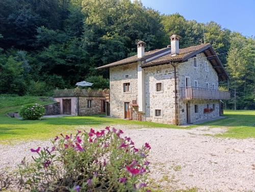 an old stone house in a field with flowers at Mulino Baiar in Stregna
