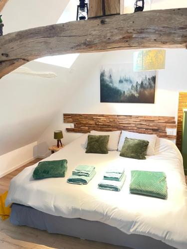 a bedroom with a bed with white sheets and green pillows at Villa Ô Room in Chasnay
