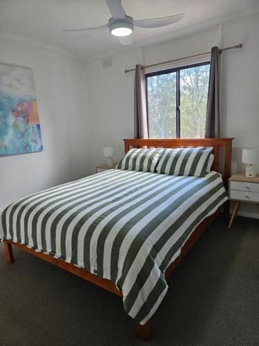 a bedroom with a bed with a striped comforter and a window at Valley Retreat in Mintaro