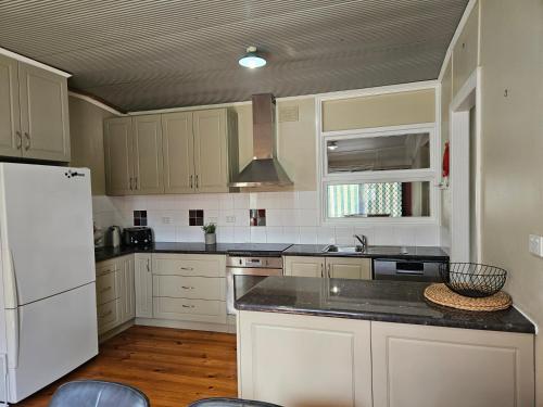 a kitchen with white cabinets and a white refrigerator at Valley Retreat in Mintaro