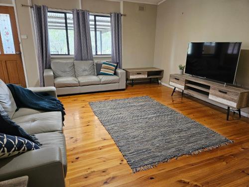 a living room with a couch and a flat screen tv at Valley Retreat in Mintaro