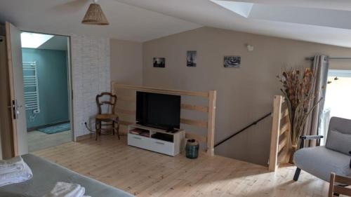 a living room with a flat screen tv and a couch at Les Volets Bleus in Bernay