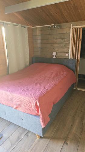 a bed with a pink comforter in a room at Le Chalet des Dany in Saint-Mamert-du-Gard