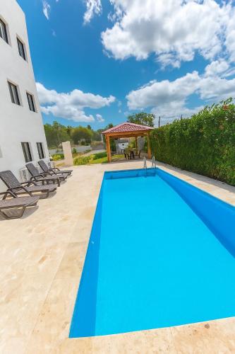 a blue swimming pool with chairs and a gazebo at Fully Serviced Apartment with 24h Power, Security and Wi-Fi in Sosúa