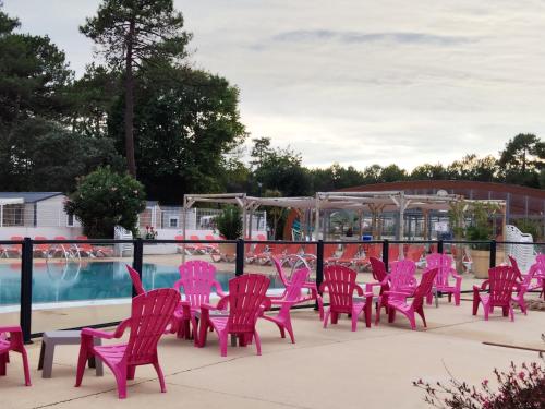 eine Gruppe rosafarbener Stühle neben einem Pool in der Unterkunft Mobil home le Sunny in Lège-Cap-Ferret