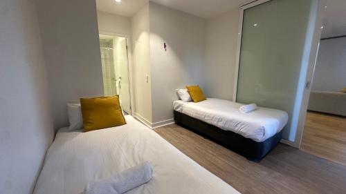 a room with two beds with yellow pillows at Nest Apartments on Rose Lane in Melbourne
