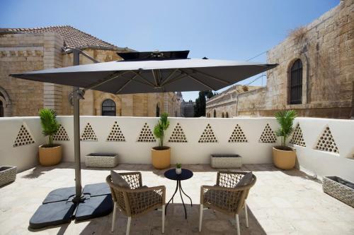 a patio with a table and two chairs and an umbrella at Petrakis Inn in Jerusalem