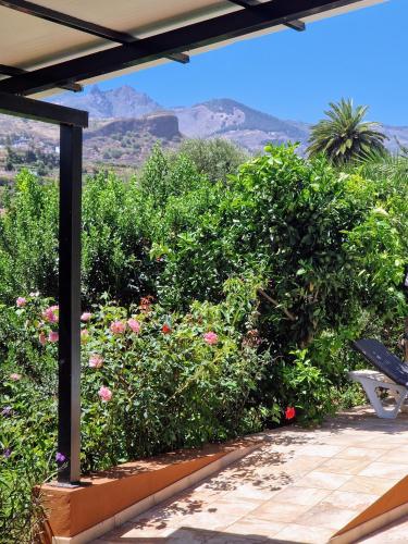 a bench on a patio with flowers and mountains in the background at House and heated pool for your exclusive use in Santa Brígida