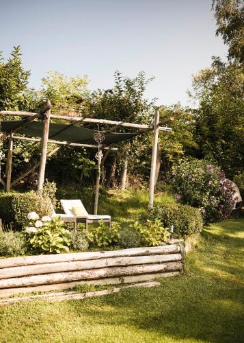 a bench under a pergola in a garden at Boutique Pension Erlacher - Adults Only in Villandro