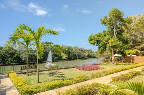 a garden with palm trees and a fence at EvaZion River Side in Grande Rivière Sud Est