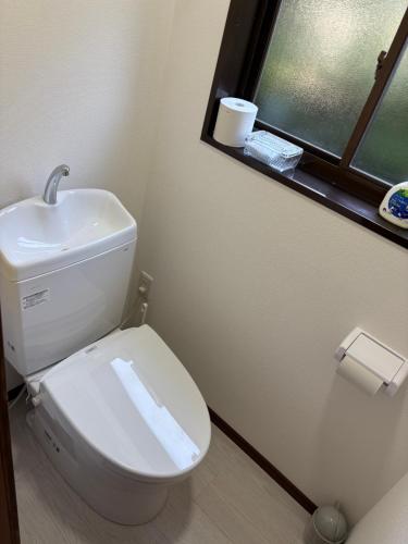 a bathroom with a toilet with a sink and a window at 多賀三宿 in Taga